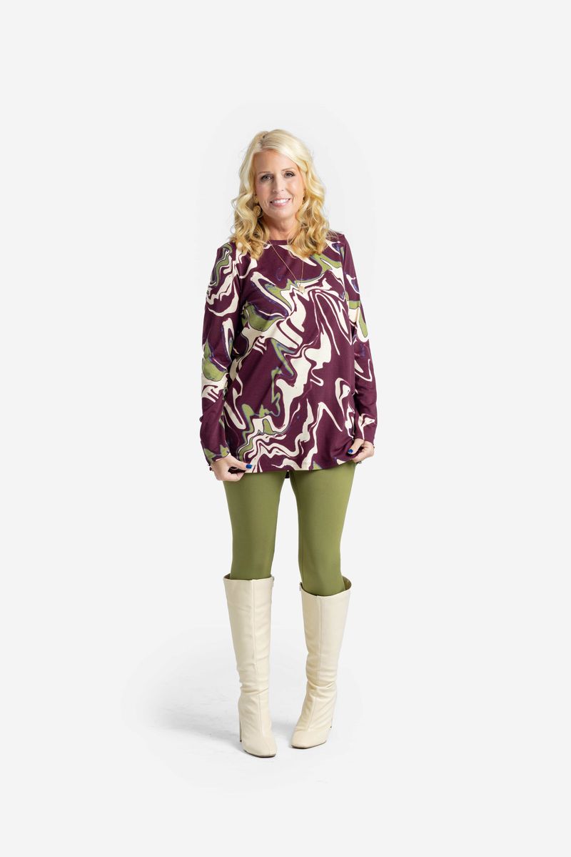 Woman wearing a LuLaRoe Sharon Long Sleeve Top in a maroon, olive, and cream marble swirl print, shown front-facing against a white background. 