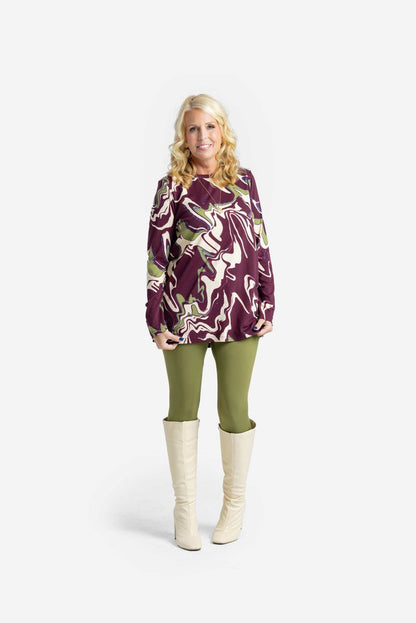 Woman wearing a LuLaRoe Sharon Long Sleeve Top in a maroon, olive, and cream marble swirl print, shown front-facing against a white background. 