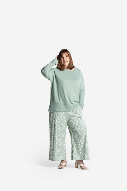 Model wearing LuLaRoe Tammy Top in soft sage green solid with relaxed fit and long sleeves on a white background