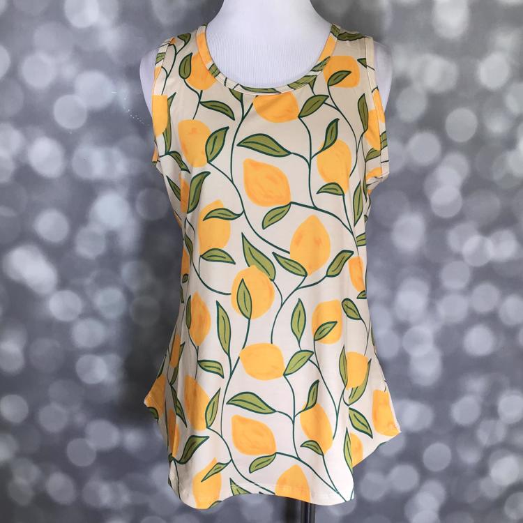 LuLaRoe beige tank top with yellow lemon print and green leaves, featuring a scoop neckline, sleeveless design, and relaxed fit displayed on a mannequin