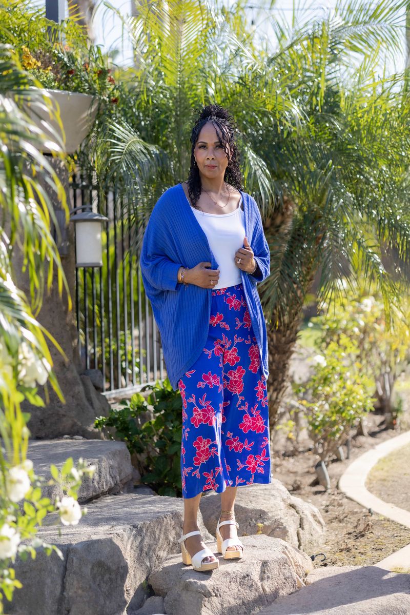 Model wearing LuLaRoe Tracy cocoon cardigan in bright cobalt blue layered over a white top and blue floral skirt, featuring a relaxed draped fit and lightweight ribbed texture styled outdoors