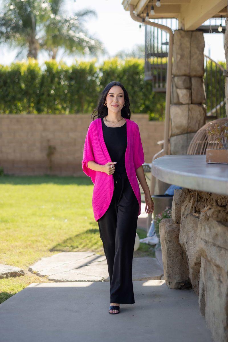 Model wearing LuLaRoe Tracy cocoon cardigan in bright fuchsia pink layered over a black outfit, featuring a relaxed draped fit and lightweight ribbed texture styled outdoors.