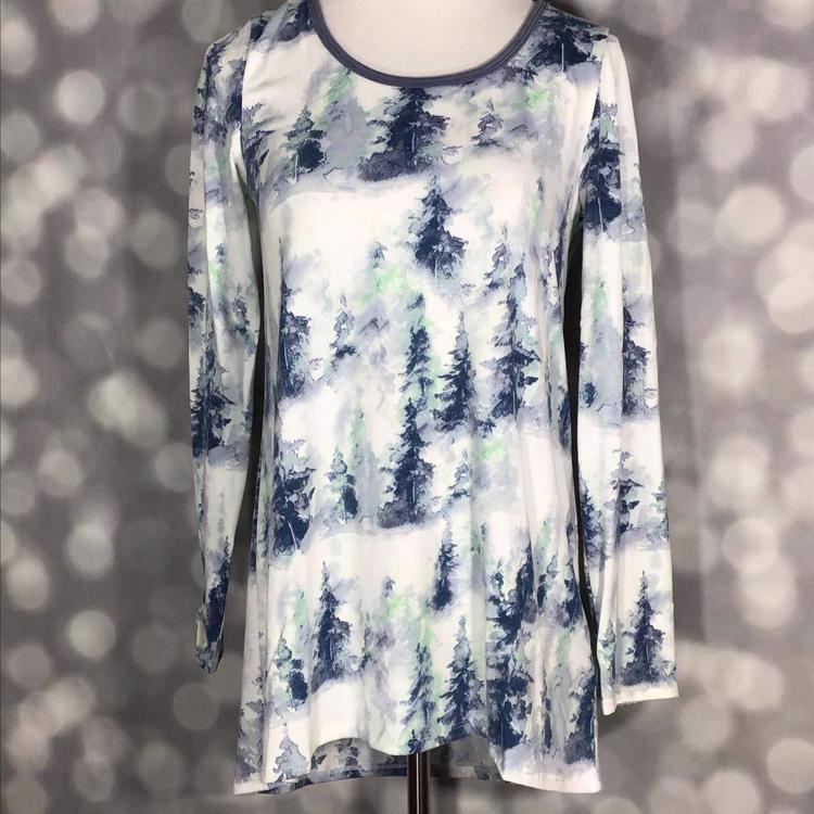 Front view of mannequin wearing LuLaRoe Lynnae Top in white fabric with watercolor-style pine tree print in blue and green tones