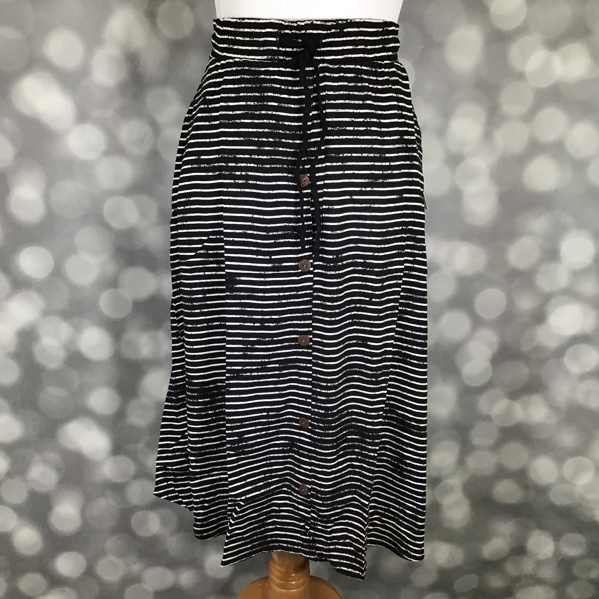 LuLaRoe Marsha Skirt with button-front detail featuring black and white horizontal stripe print with elastic waistband on a mannequin against a blurred background