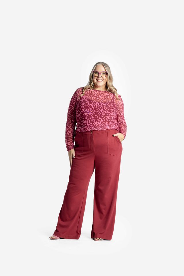 Woman wearing a LuLaRoe May long sleeve mesh top in raspberry red with pink abstract floral doodle pattern, fitted silhouette, lightweight semi-sheer mesh fabric styled on a white background