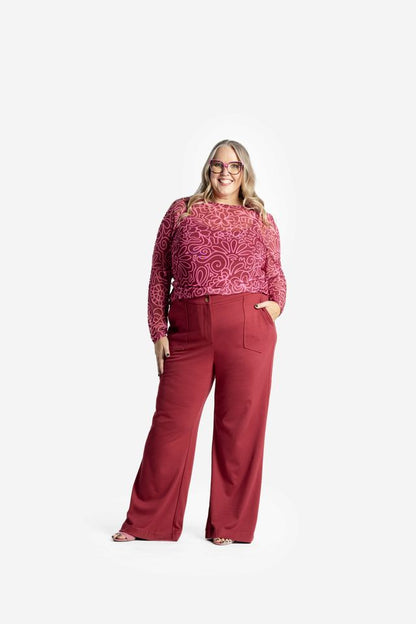 Woman wearing a LuLaRoe May long sleeve mesh top in raspberry red with pink abstract floral doodle pattern, fitted silhouette, lightweight semi-sheer mesh fabric styled on a white background