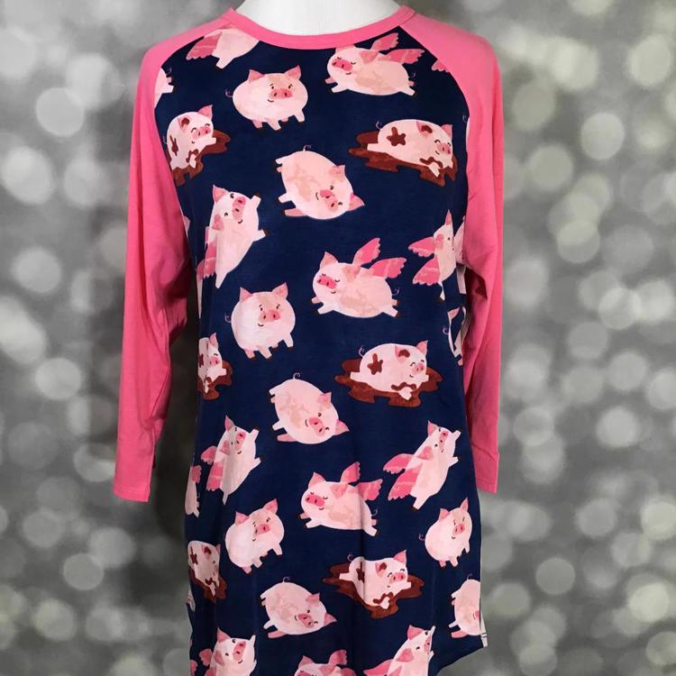 LuLaRoe Randy Tee with navy background and pink flying pig print with solid pink sleeves on a mannequin with a gray blurred background.