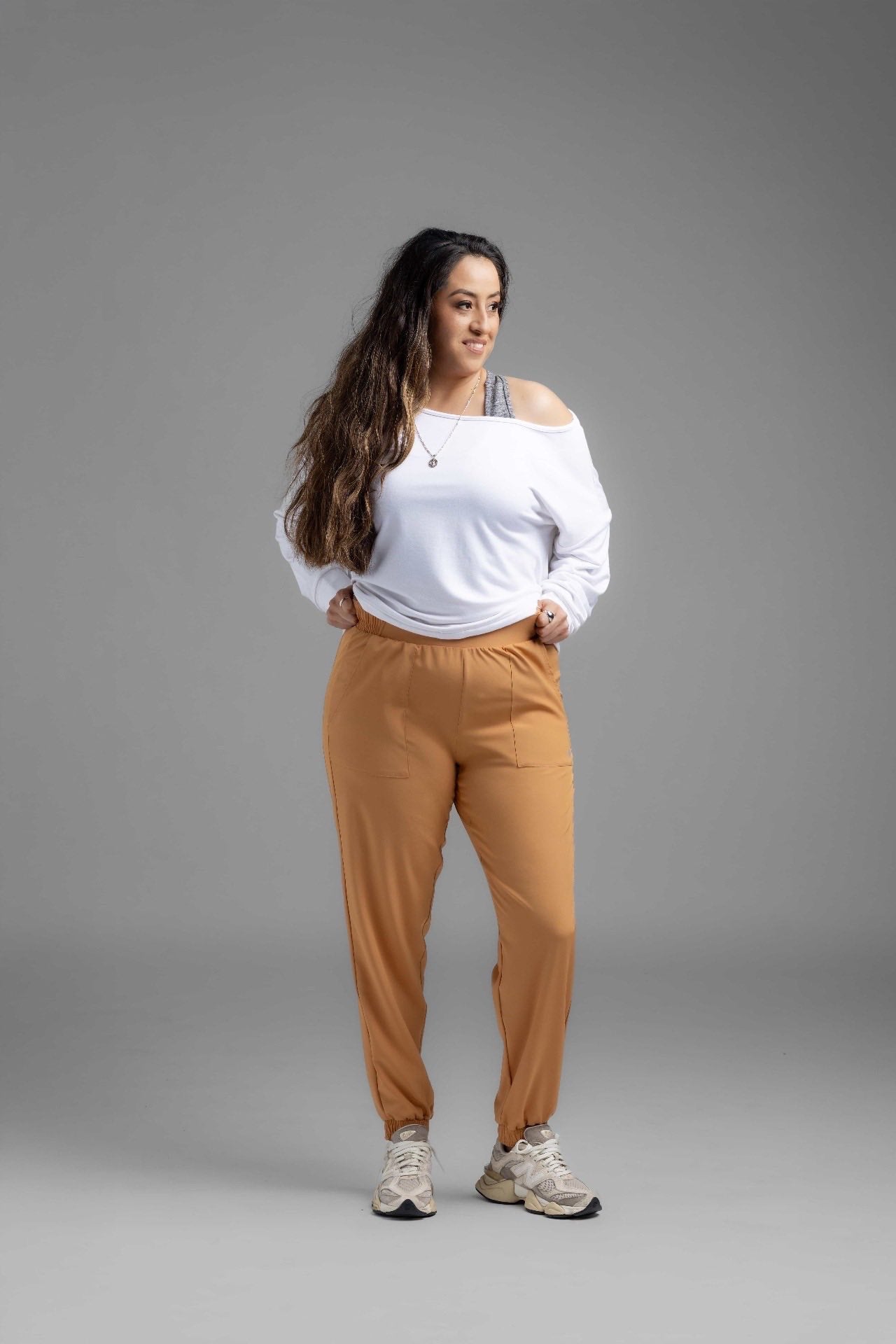 Model wearing LuLaRoe Rise Infinite Jogger in solid camel tan with elastic waistband and jogger cuffs