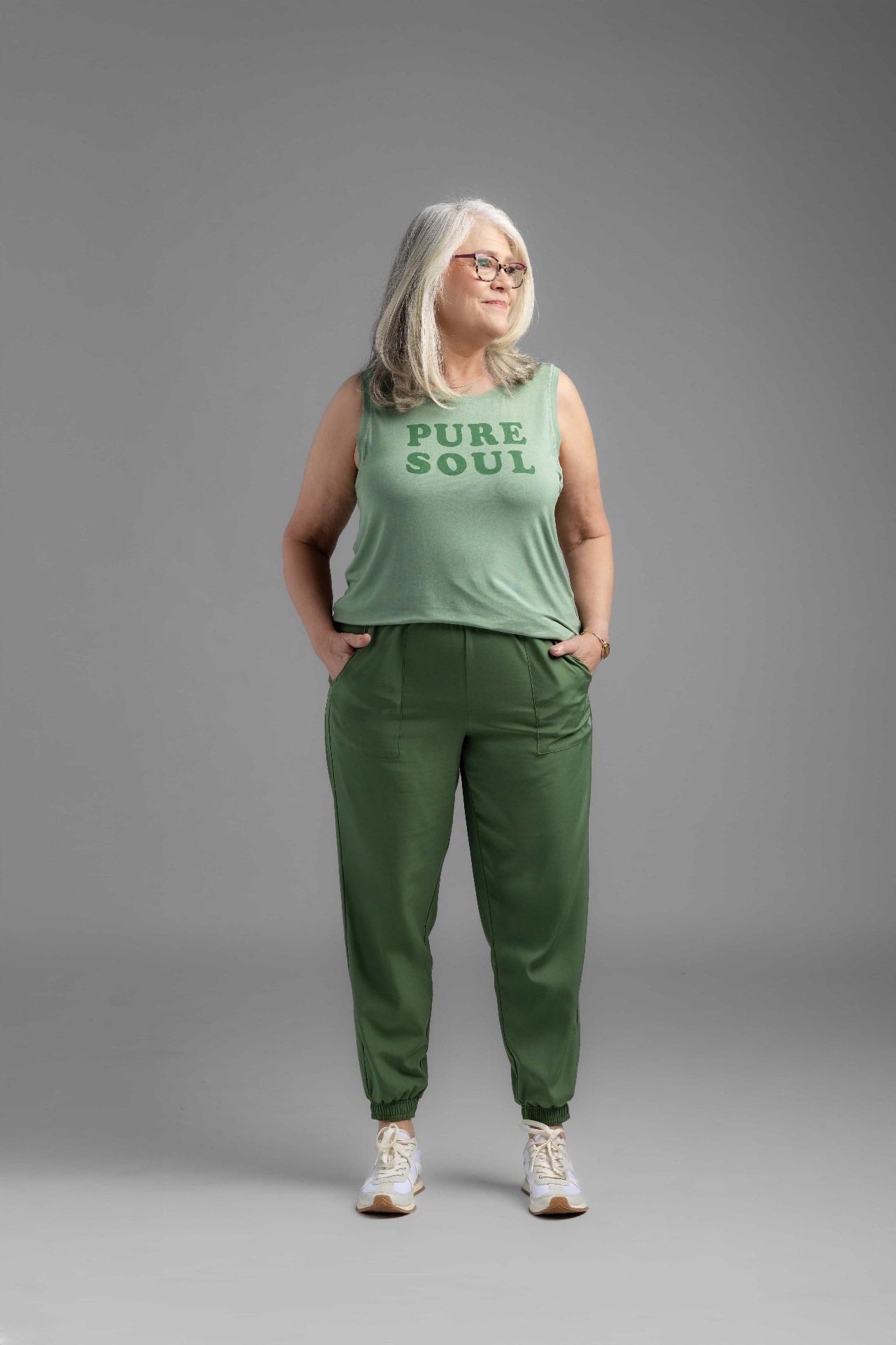 Woman wearing solid green Rise Infinite Joggers with elastic waistband and cuffed ankles, styled casually with sneakers