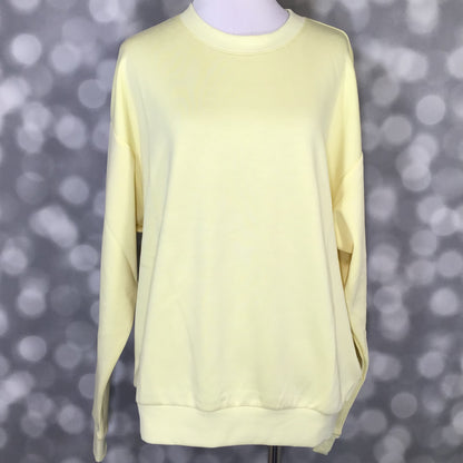 Rise Reset Crewneck Pullover in solid buttercream yellow with an oversized relaxed fit and ribbed hem on a mannequin against a blurred gray background