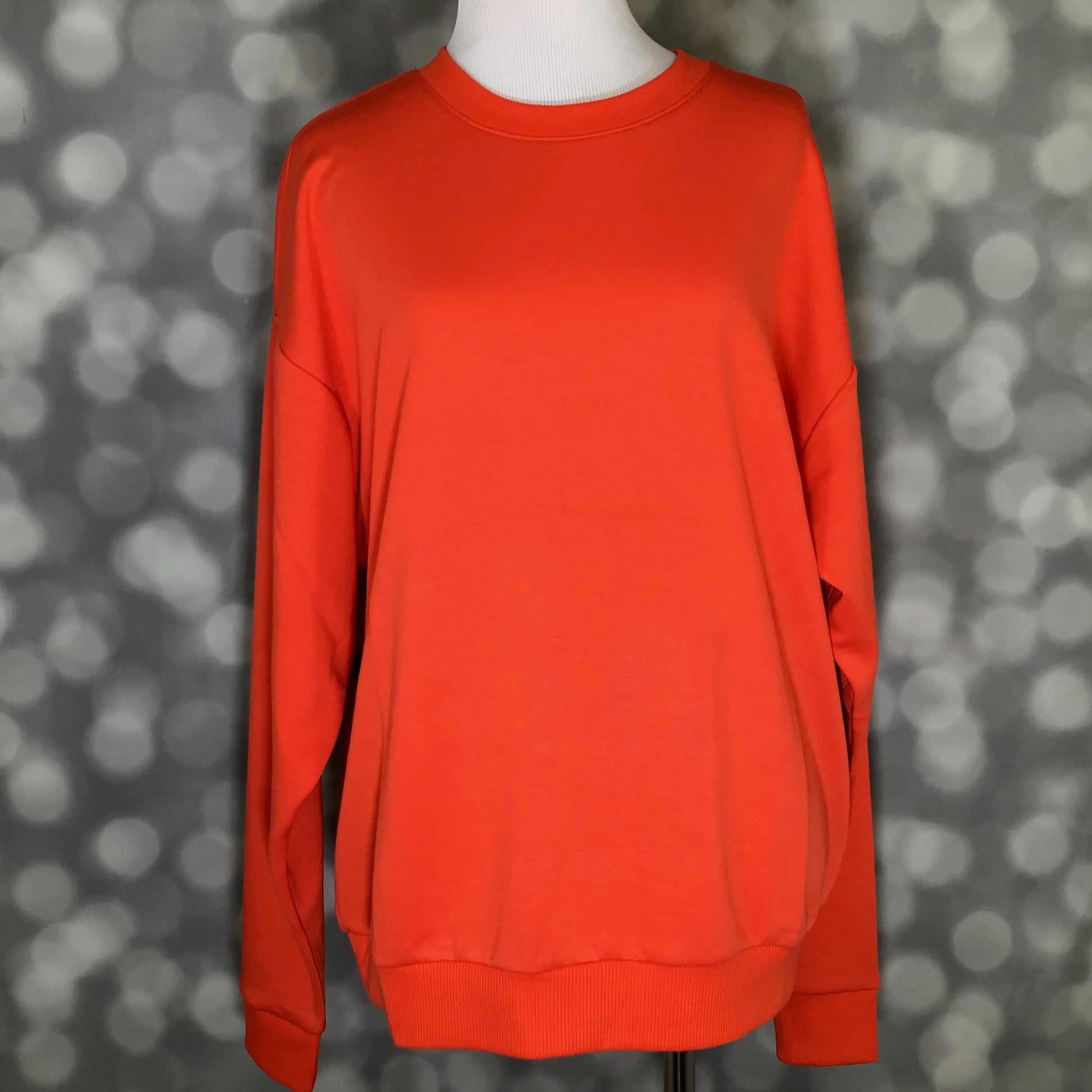 Rise Reset Crewneck Pullover in solid poppy red with an oversized relaxed fit and ribbed hem on a mannequin against a blurred gray background