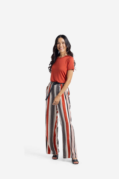 Woman wearing LuLaRoe Essential Tee in Solid Canyon Clay featuring a warm clay red-orange color, classic crew neckline, short sleeves, and a semi-relaxed fit in soft luxe modal fabric on a white background