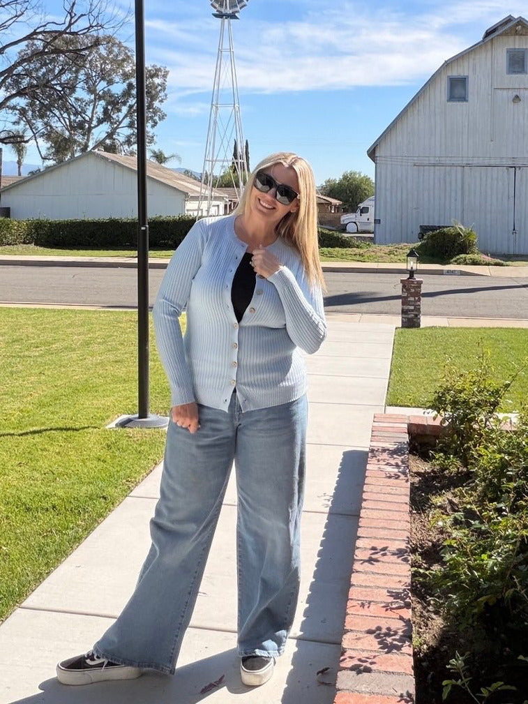 Woman standing on a sidewalk with a barn and windmill in the background