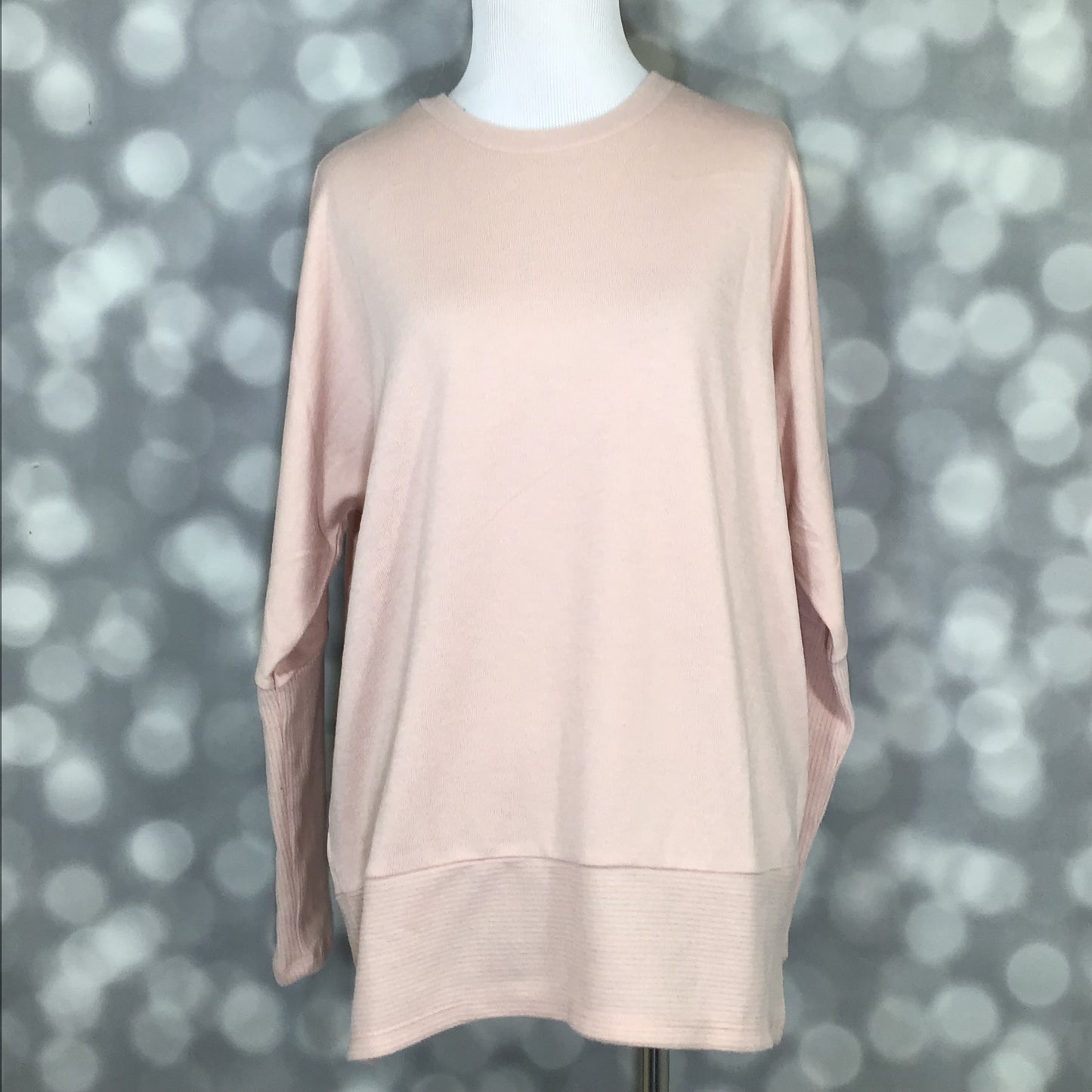 LuLaRoe Tammy top in solid soft blush pink with long sleeves, relaxed fit, ribbed cuffs and hem, made from brushed Hacci fabric on a mannequin against a blurred gray background